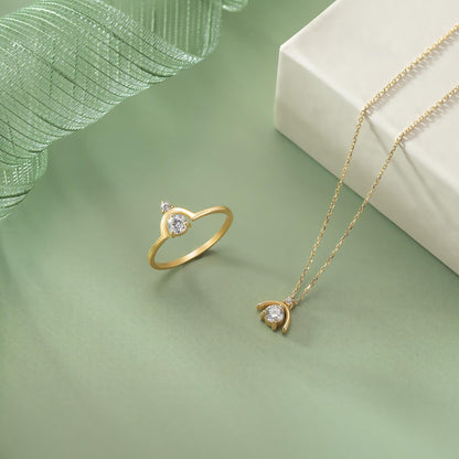 a gold ring and necklace with a pendant on a green background.