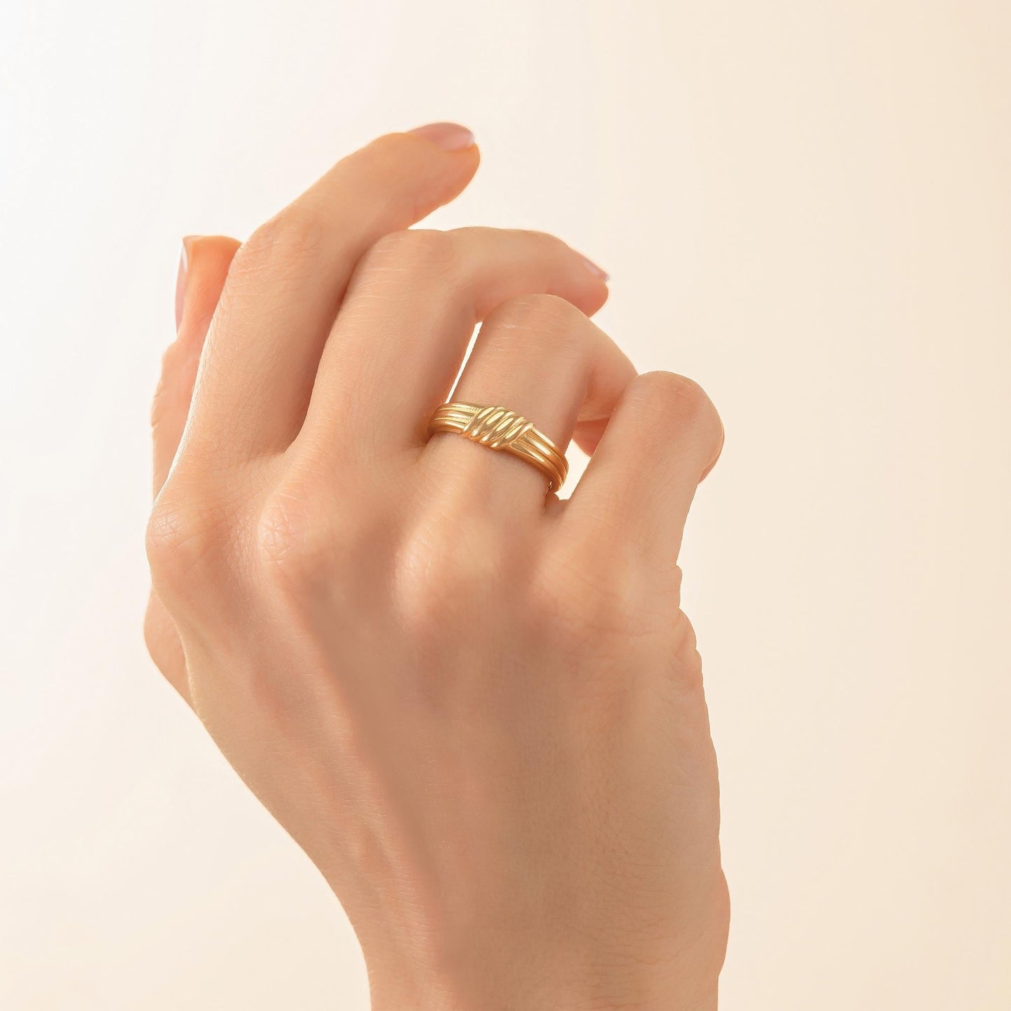 A close-up of a hand wearing a gold ring on the ring finger.