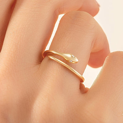 A close-up of a person's hand wearing a gold snake-shaped ring with a diamond accent.