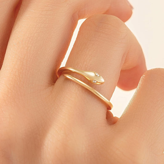 A close-up of a person's hand wearing a gold snake-shaped ring with a diamond accent.