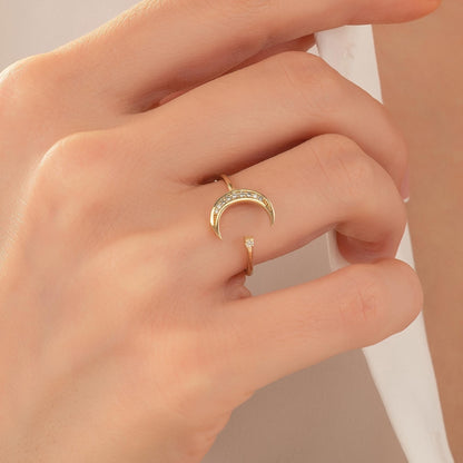 A close-up view of a person's hand wearing a gold ring with a crescent moon design.