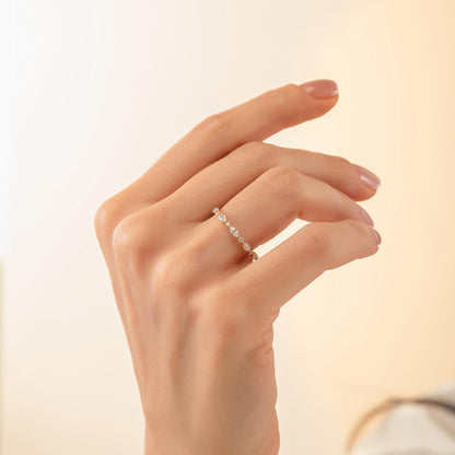 A close-up view of a hand wearing a delicate gold ring with small diamonds.