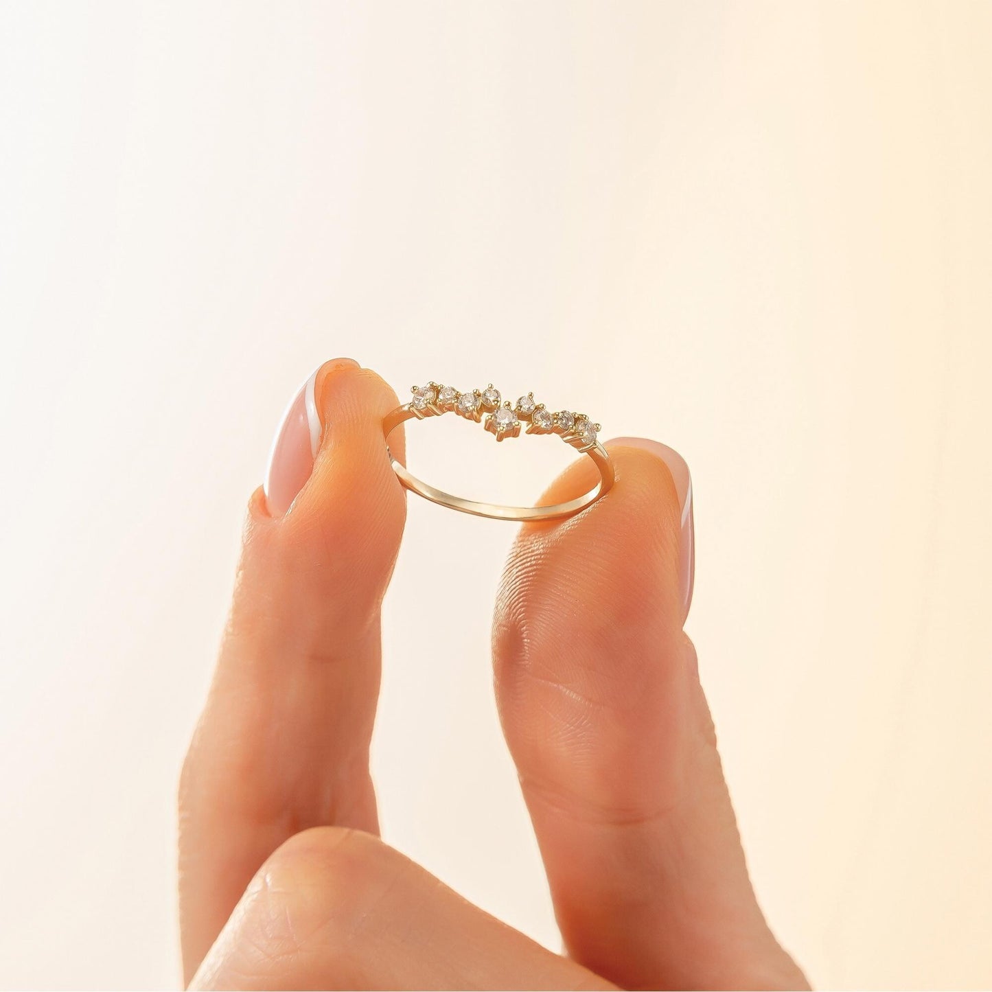 A hand holding a gold ring with small diamonds on it.