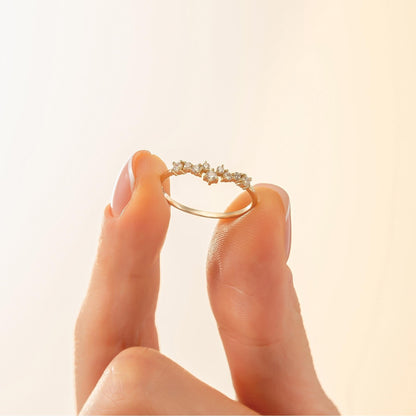 A hand holding a gold ring with small diamonds on it.