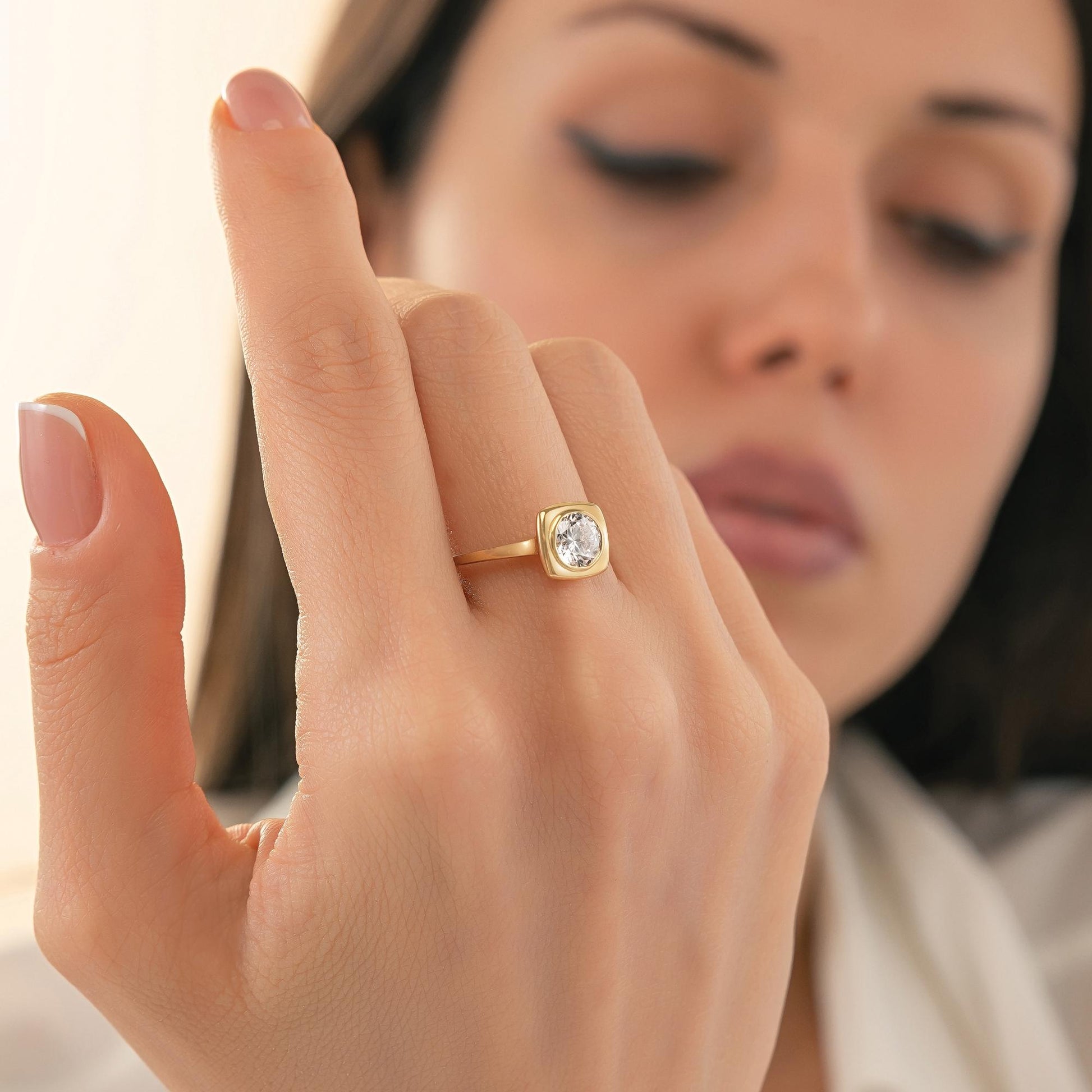 A close-up of a person's hand wearing a gold ring with a large diamond in the center.