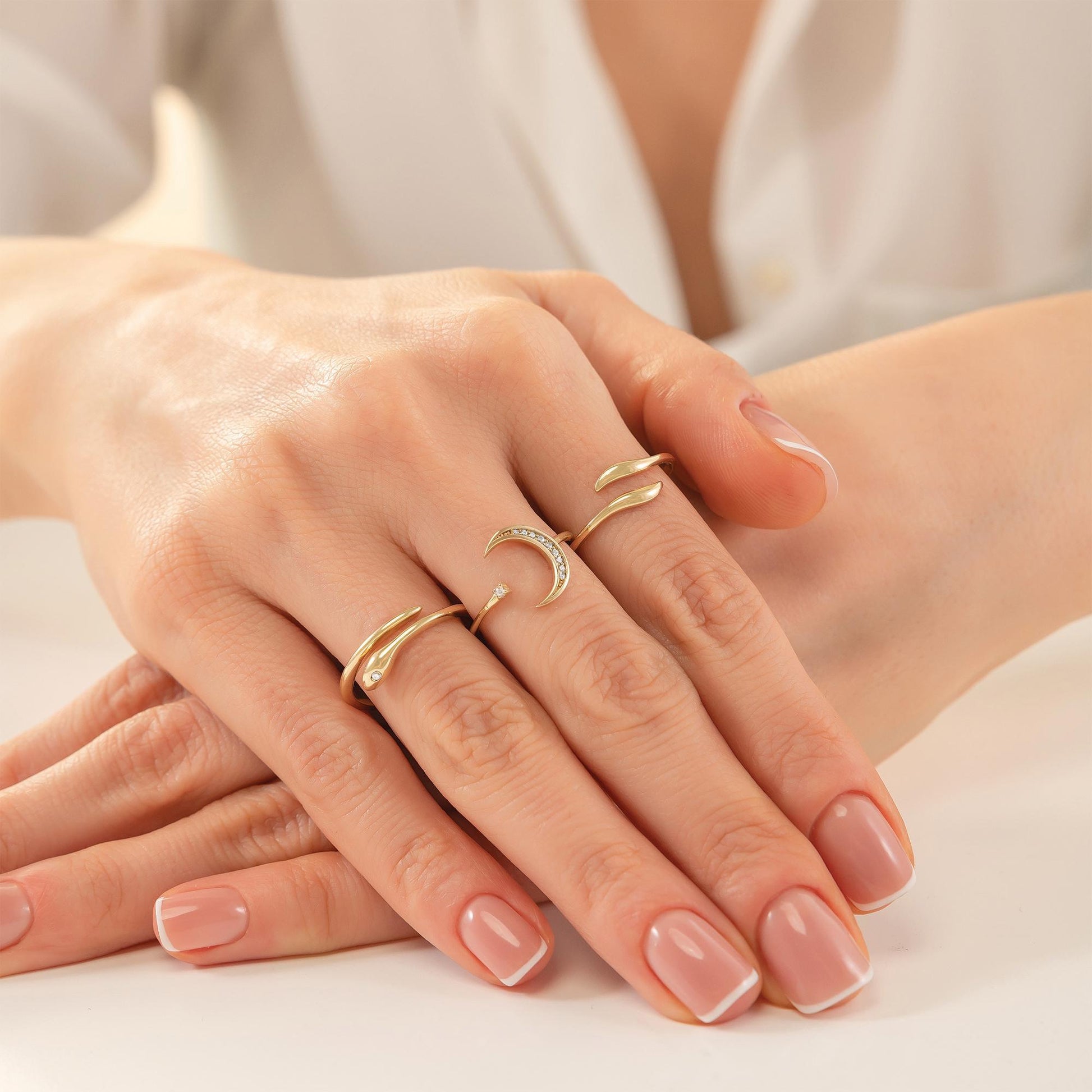 A close-up image of a person's hands wearing multiple rings on their fingers.