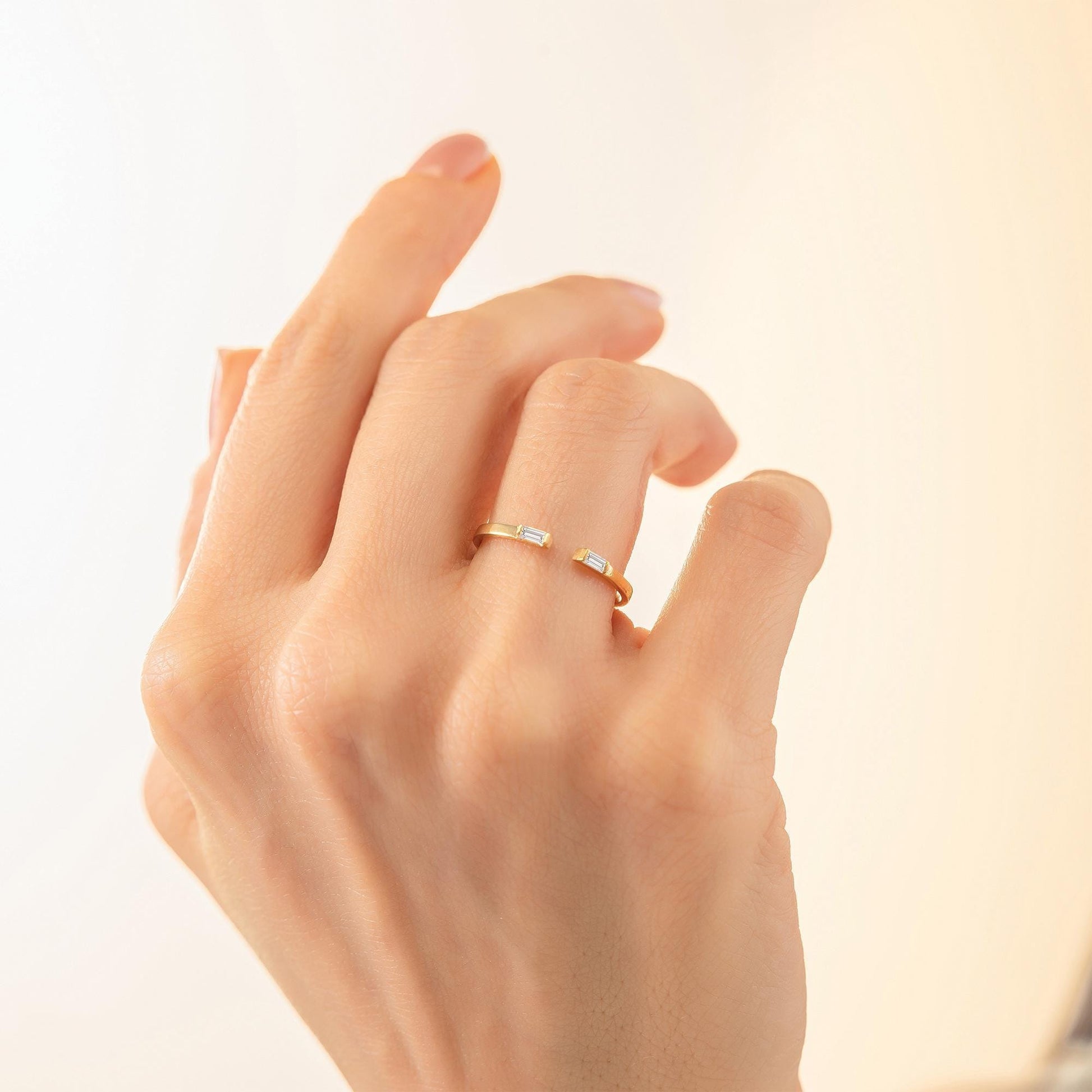 A close-up of a person's hand wearing a gold ring with a unique design.