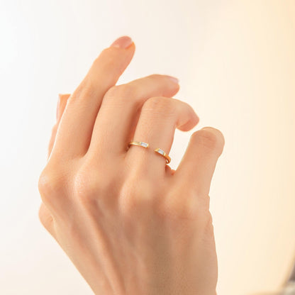 A close-up of a person's hand wearing a gold ring with a unique design.