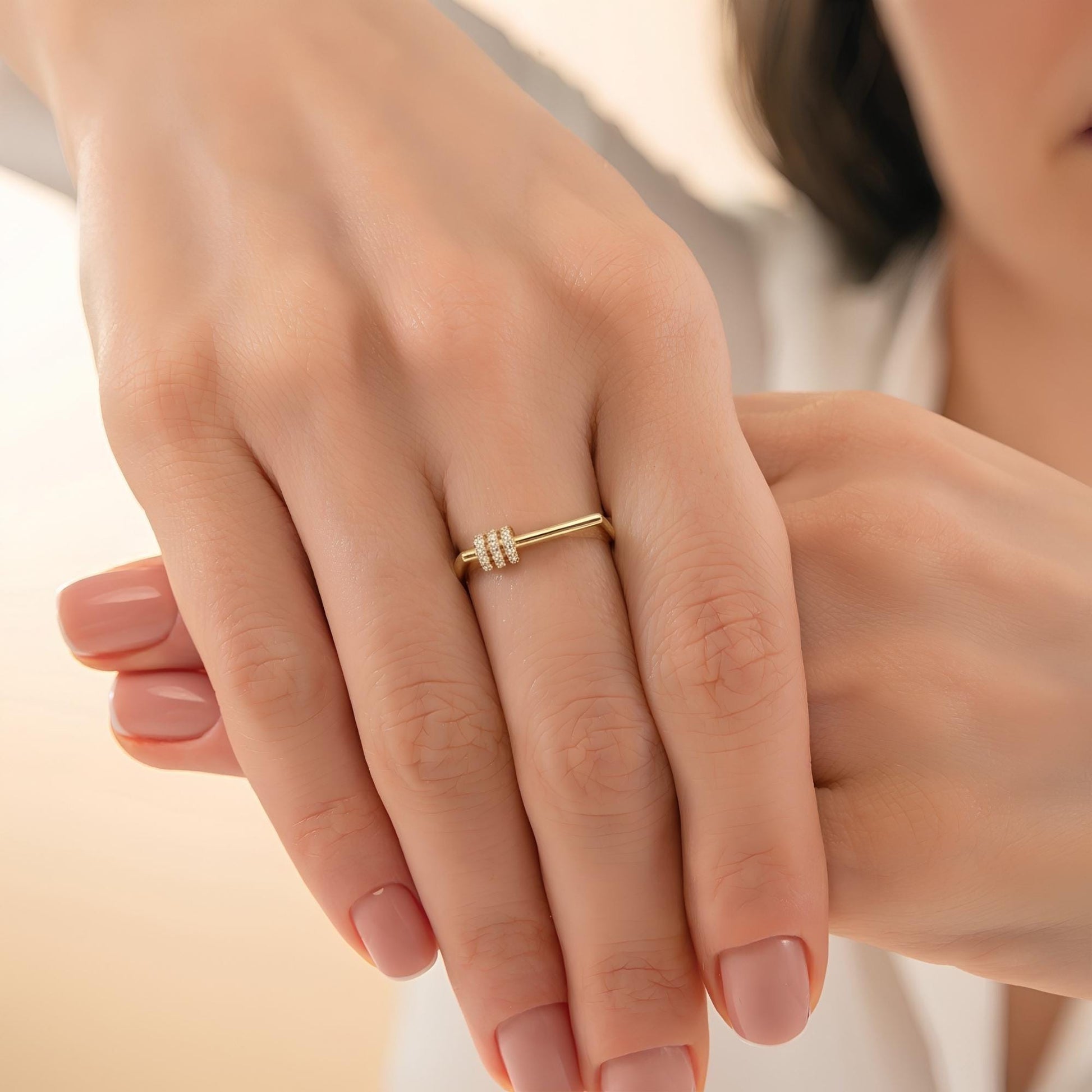 A close-up of a person's hand wearing a gold ring with a small diamond.