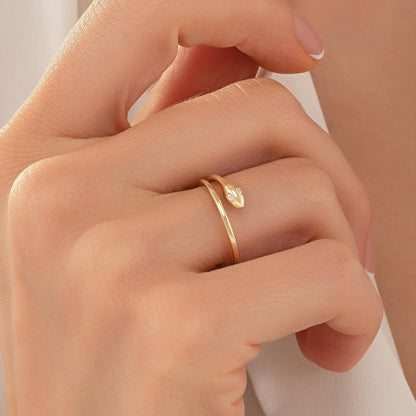 A close-up of a person's hand wearing a gold ring with a snake design.
