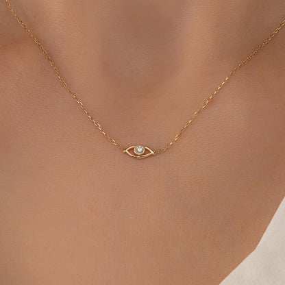 A delicate gold necklace with a small diamond pendant, featuring a single eye design.