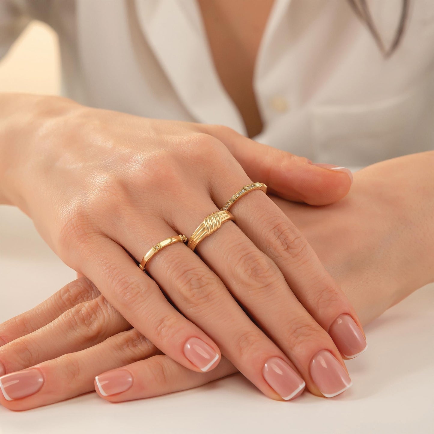 A close-up image of a person's hands wearing three rings on their fingers.