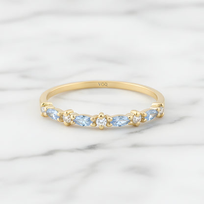 A gold ring with blue gemstones set in a row, placed on a marble surface.