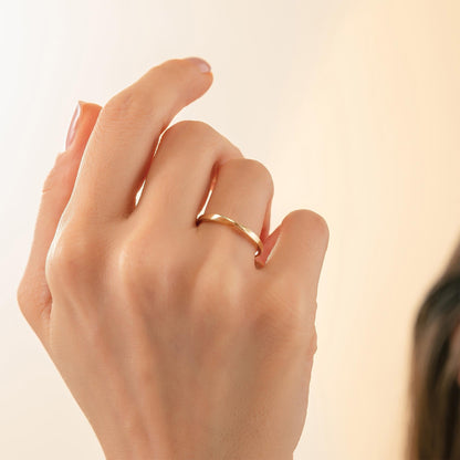 A close-up of a person's hand wearing a gold ring, with a blurred background.