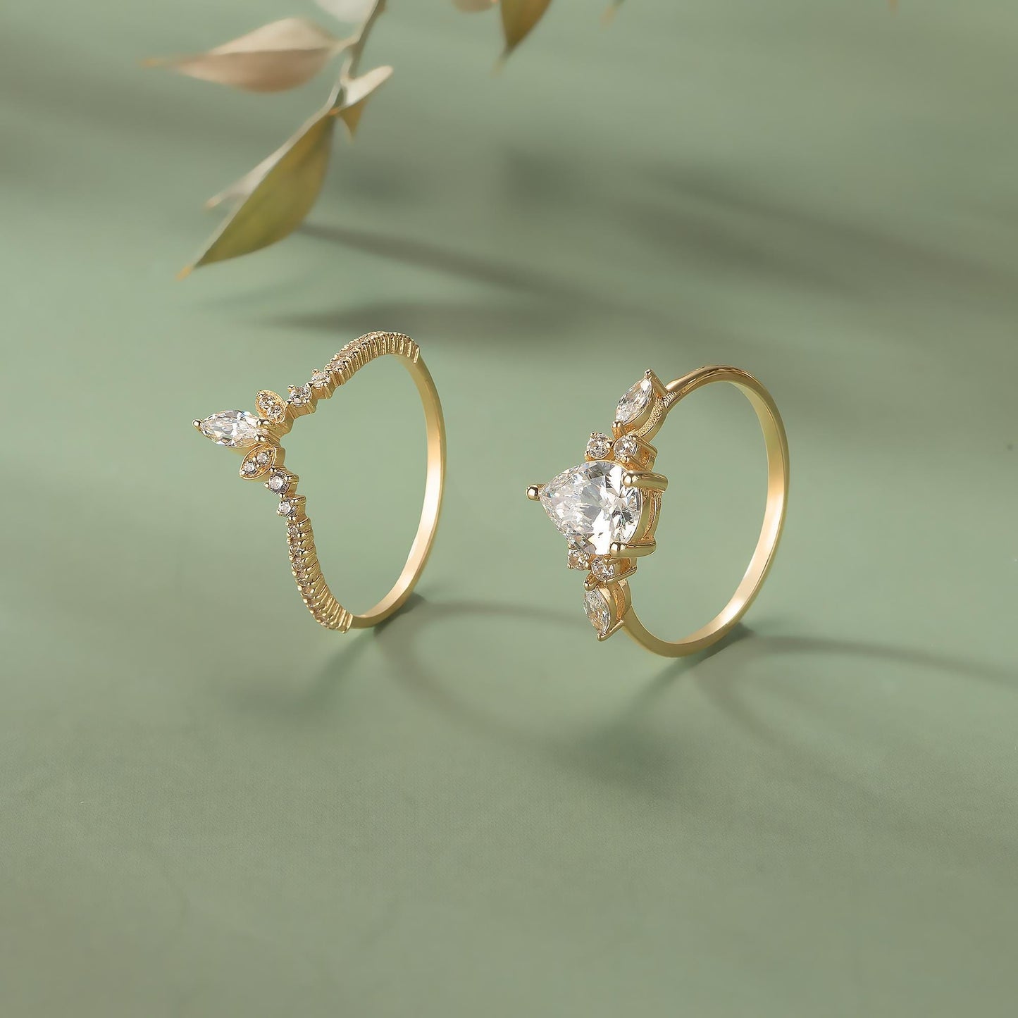 Two gold rings with diamond accents are displayed on a green background.