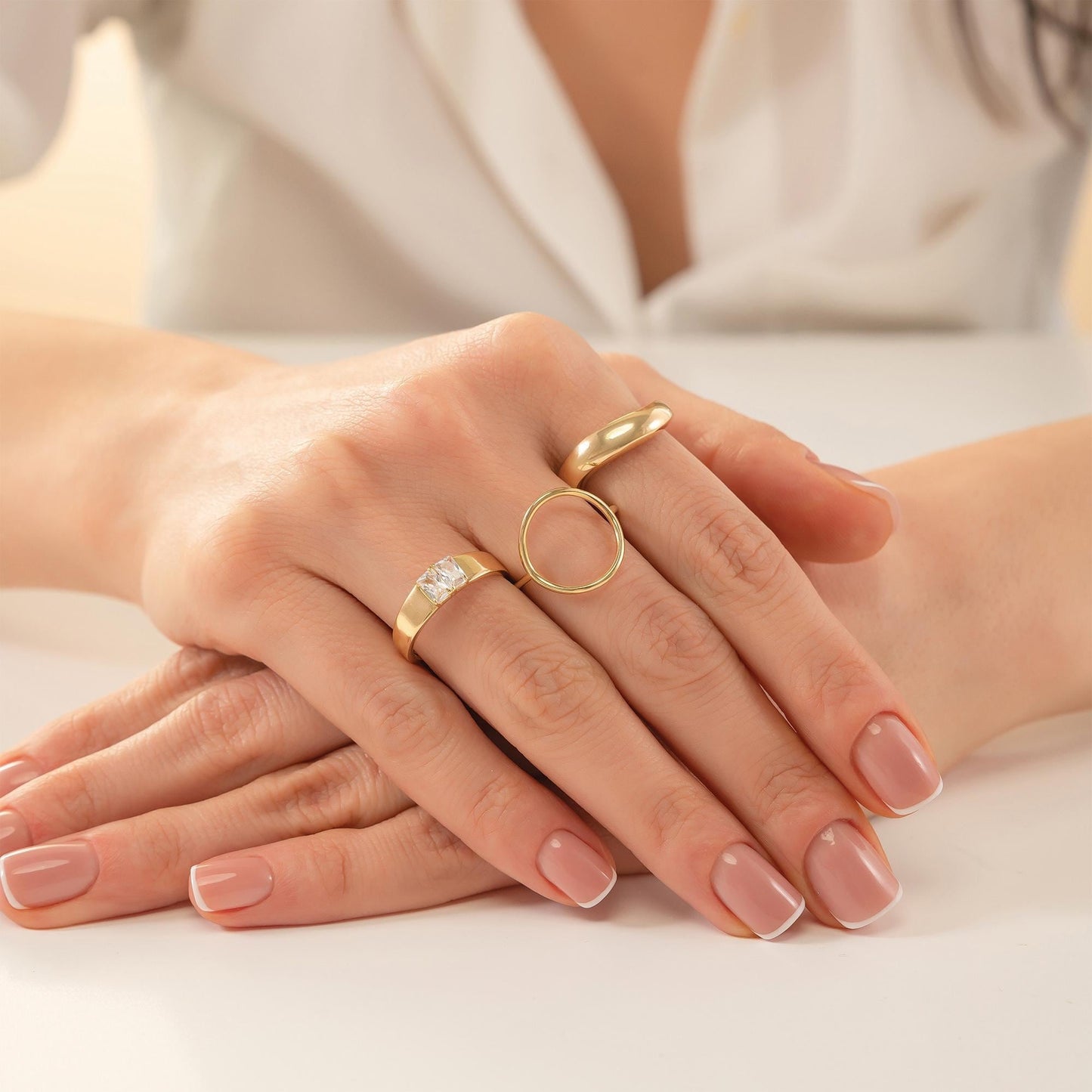 A close-up image of a person's hands wearing three rings on their fingers.