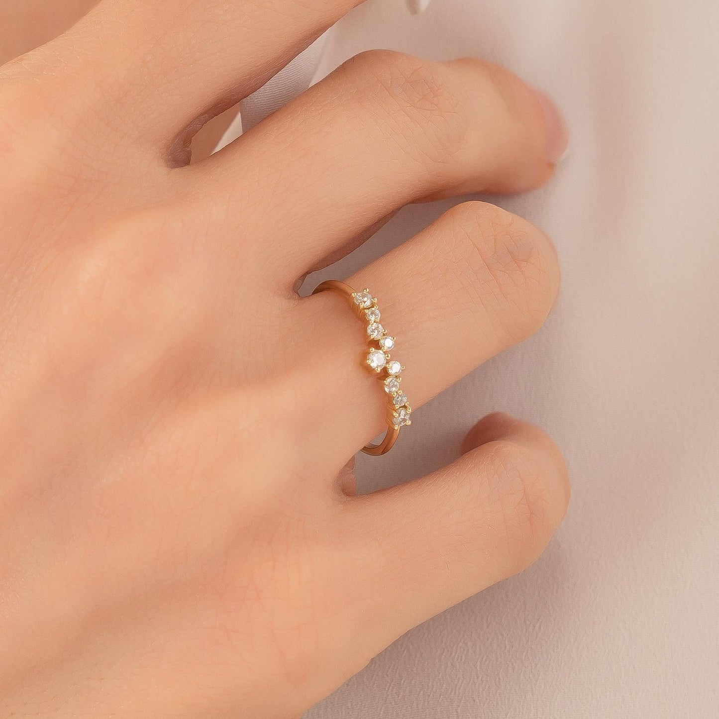 A close-up of a person's hand wearing a gold ring with a row of small diamonds on the ring finger.