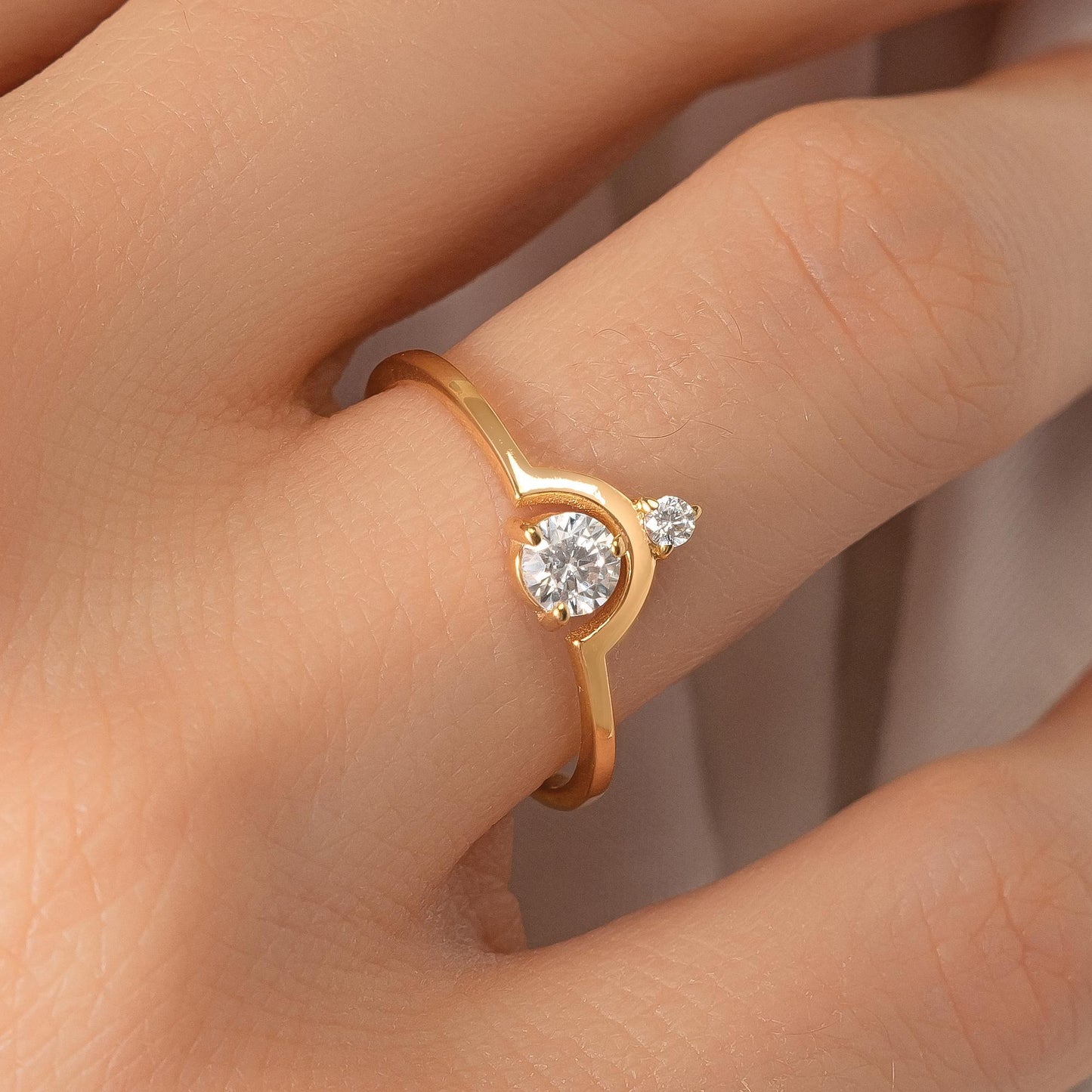 A close-up of a gold ring with a large diamond set in the center, worn on a person's hand.