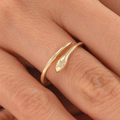 A close-up image of a gold ring with a snake design on the finger.