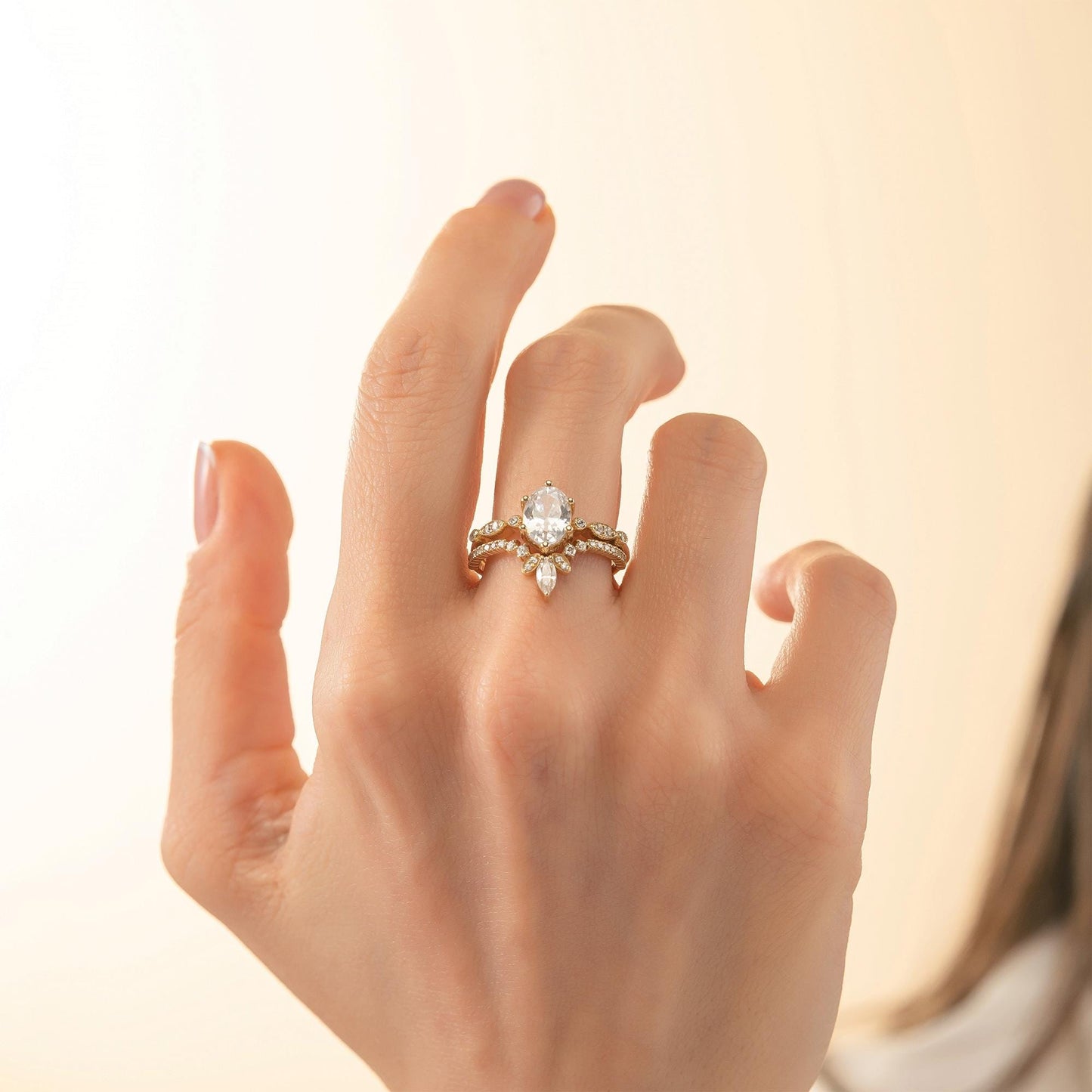 A close-up of a person's hand wearing a gold ring with a diamond center stone and a ring band.