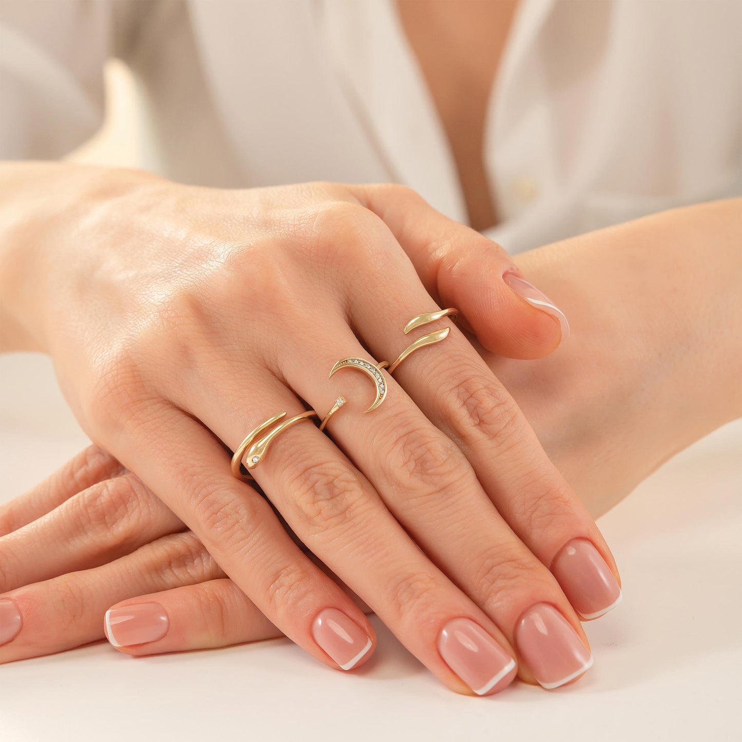 A close-up image of a person's hands wearing multiple rings on their fingers.