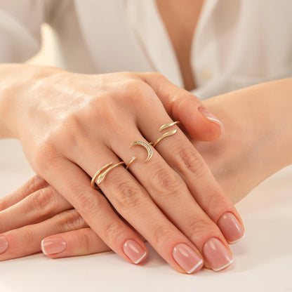 A close-up image of a person's hands wearing multiple rings on their fingers.
