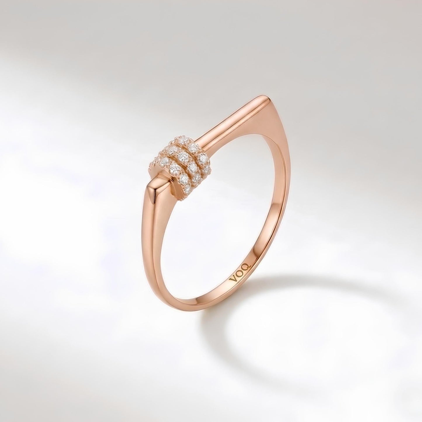 A rose gold ring with a unique design and a small cluster of diamonds set in the center.