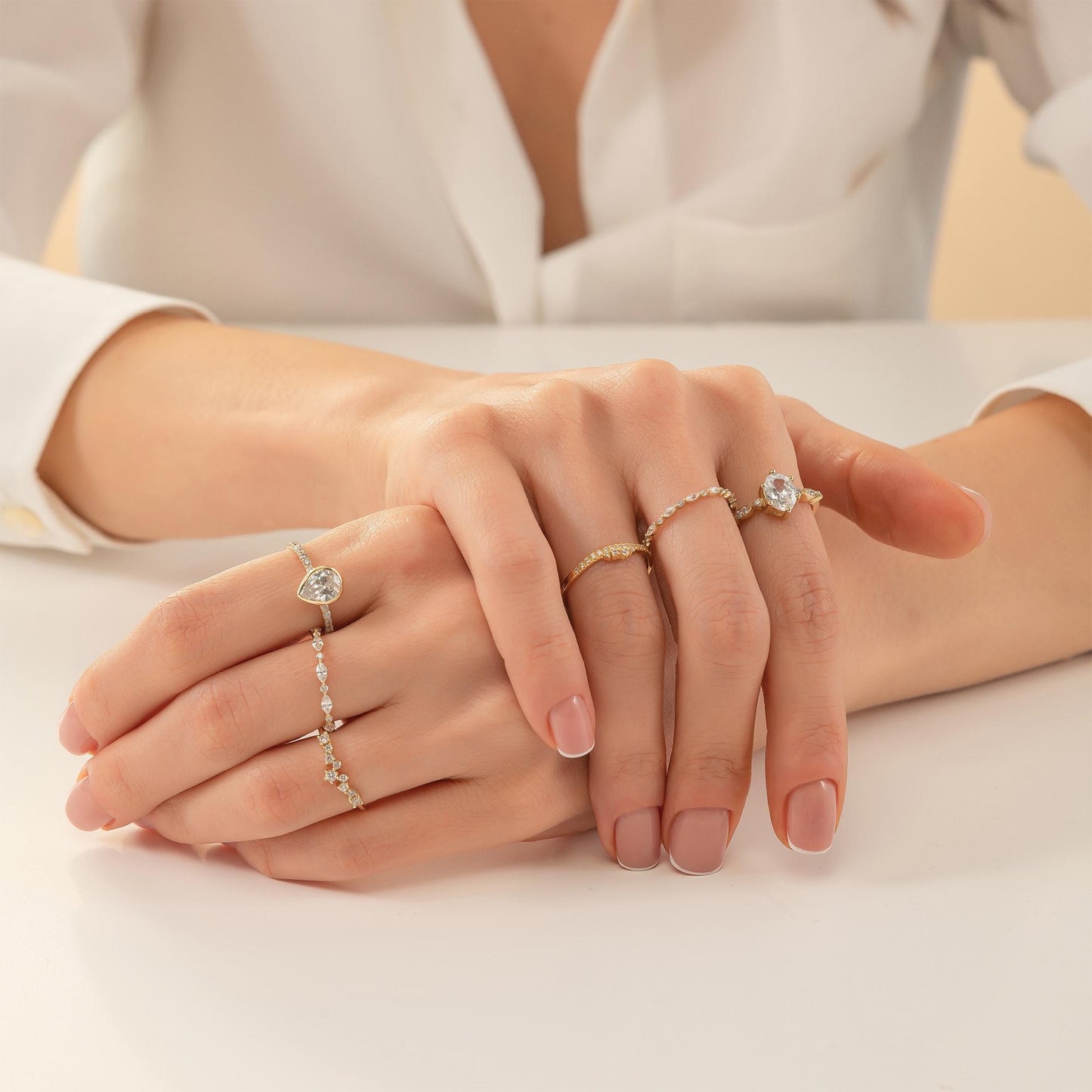 A close-up image of a person's hands wearing multiple rings on their fingers.