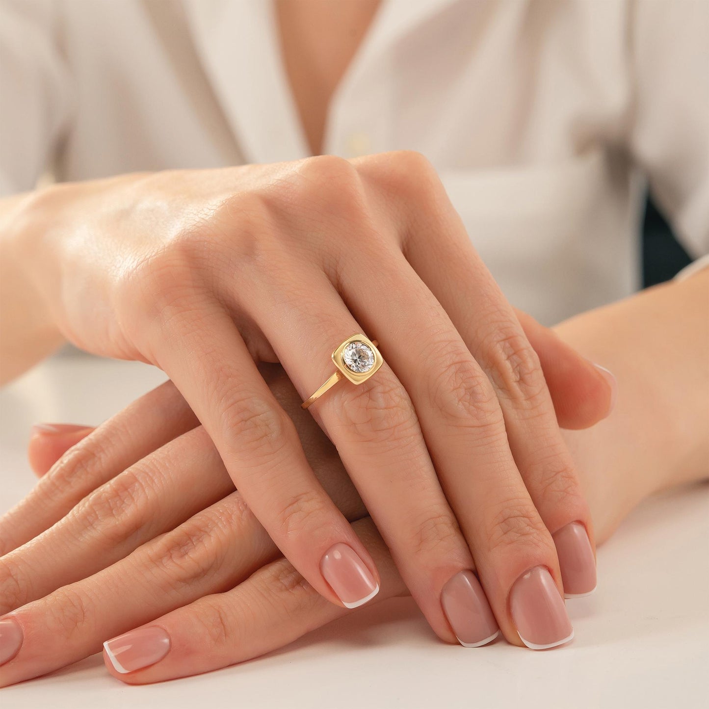 A close-up image of a person's hands wearing a gold ring with a diamond.