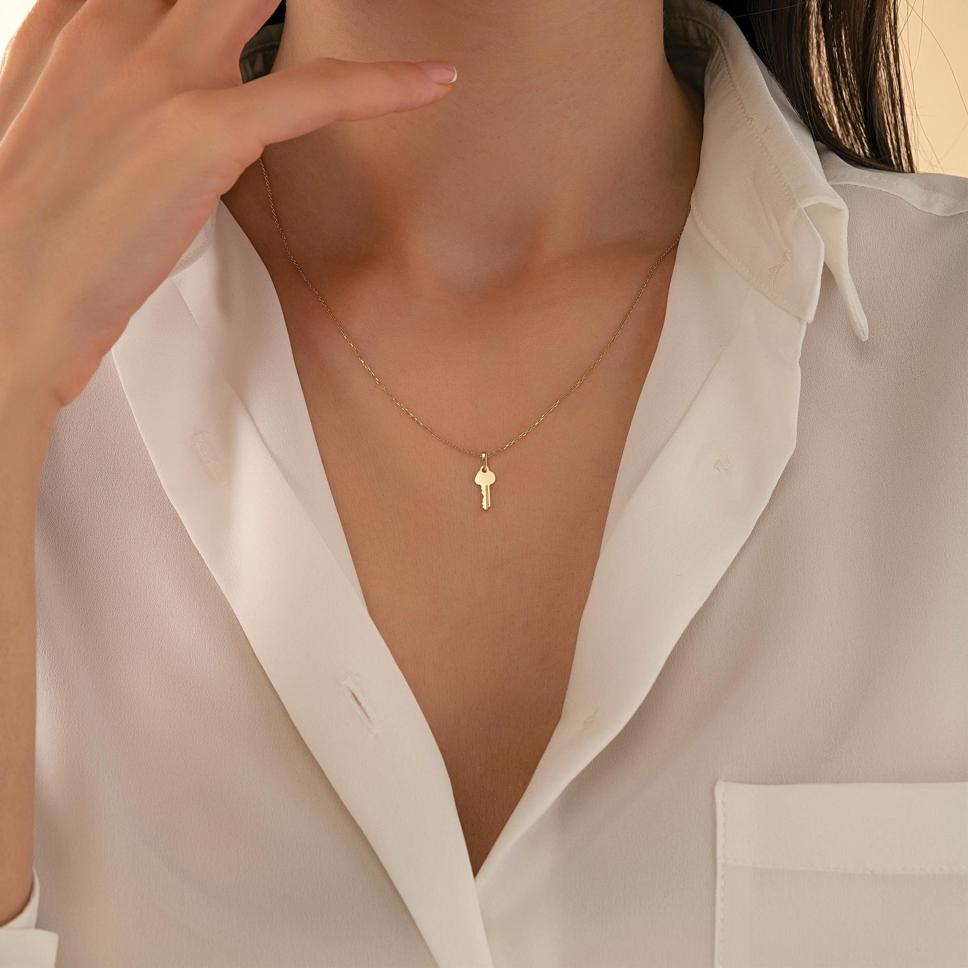 A close-up view of a person's neck and chest area, showing a delicate gold necklace with a small pendant.