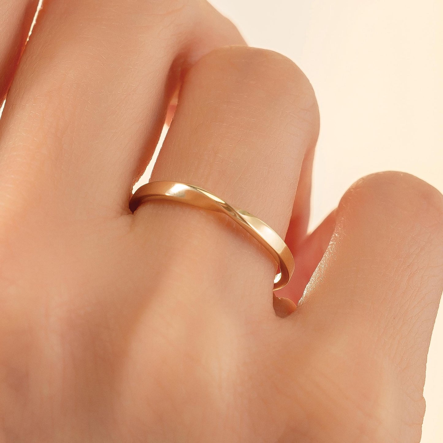 A close-up view of a person's hand wearing a gold ring on the ring finger.