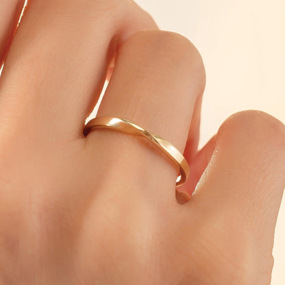A close-up view of a person's hand wearing a gold ring on the ring finger.