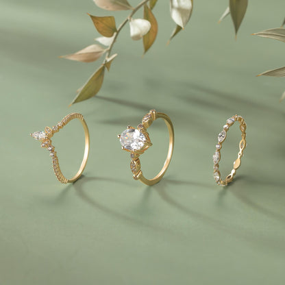 Three gold rings with various designs and gemstones are displayed on a green background.