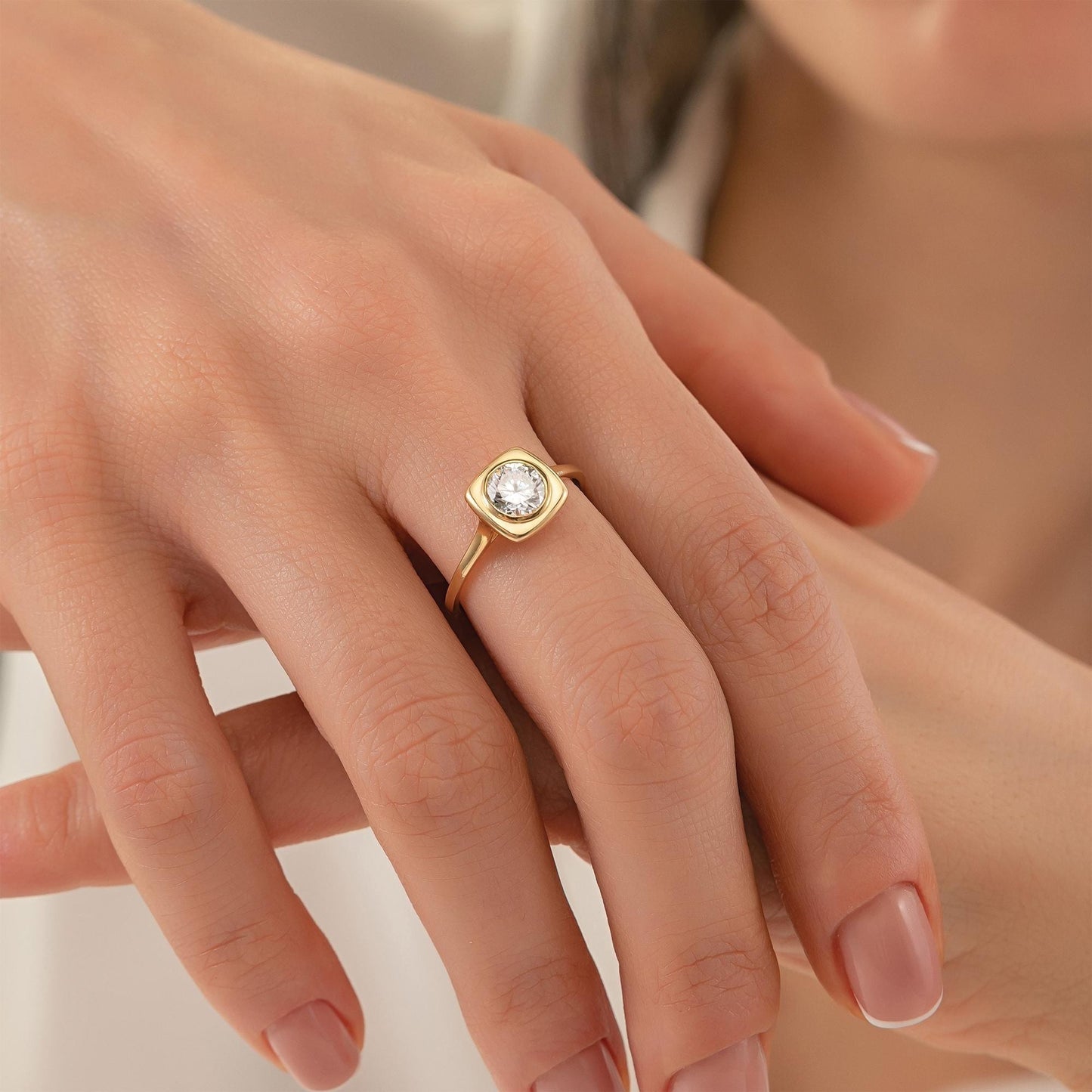 A close-up of a person's hand wearing a gold ring with a diamond.