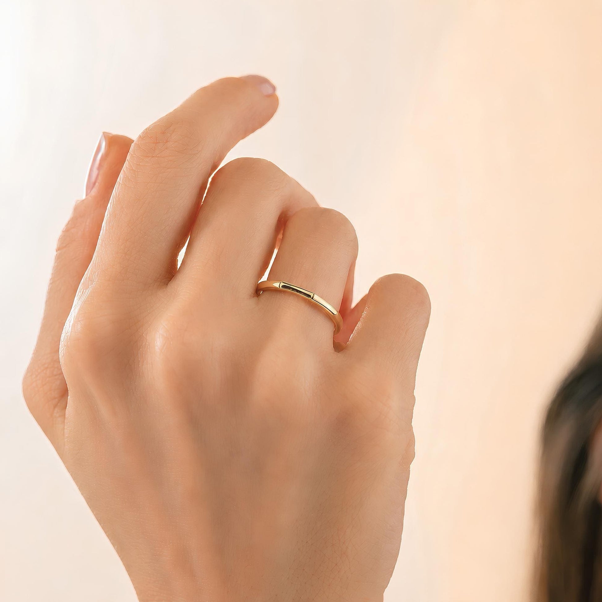 A close-up of a person's hand wearing a gold ring.
