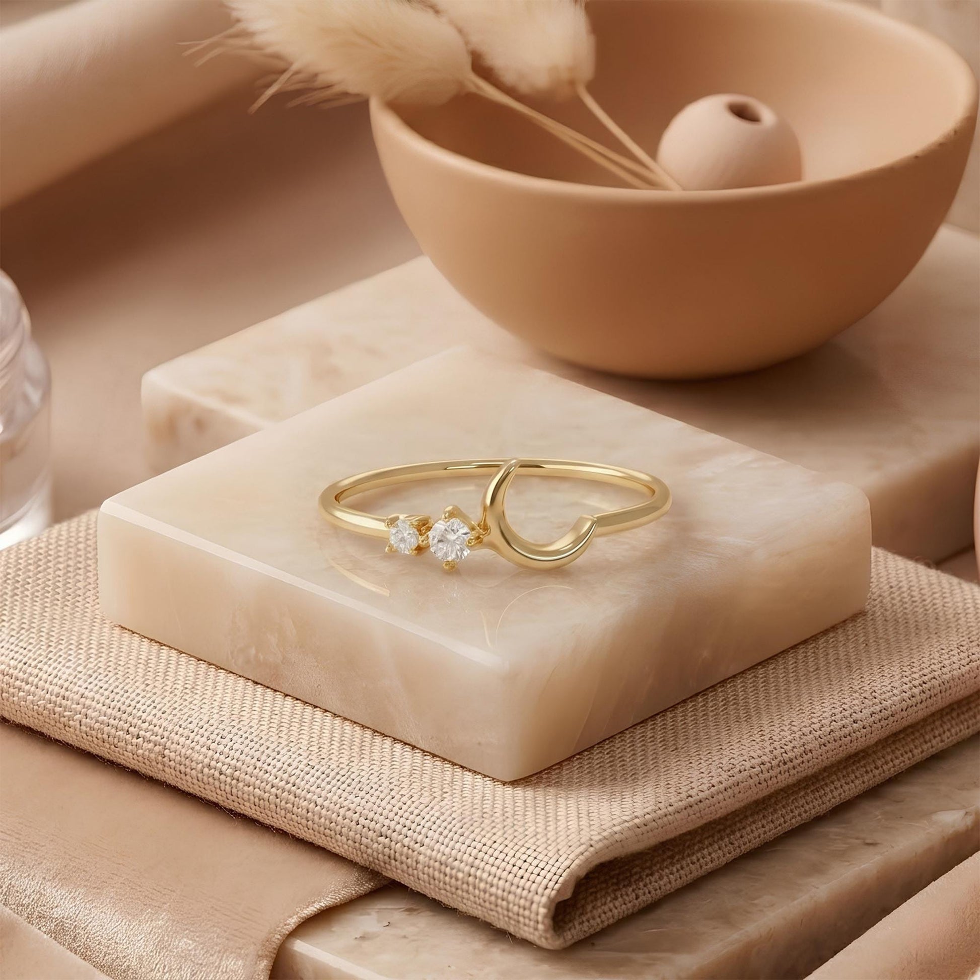 a gold ring with a crescent moon design, placed on a marble surface.