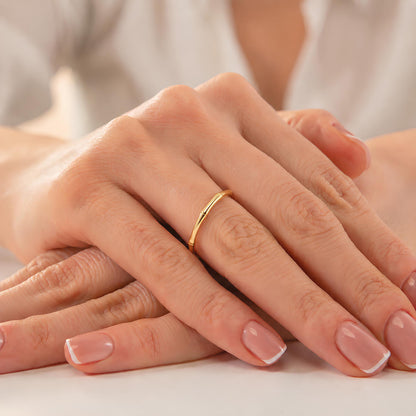 A close-up image of a person's hands with a gold ring on the ring finger.