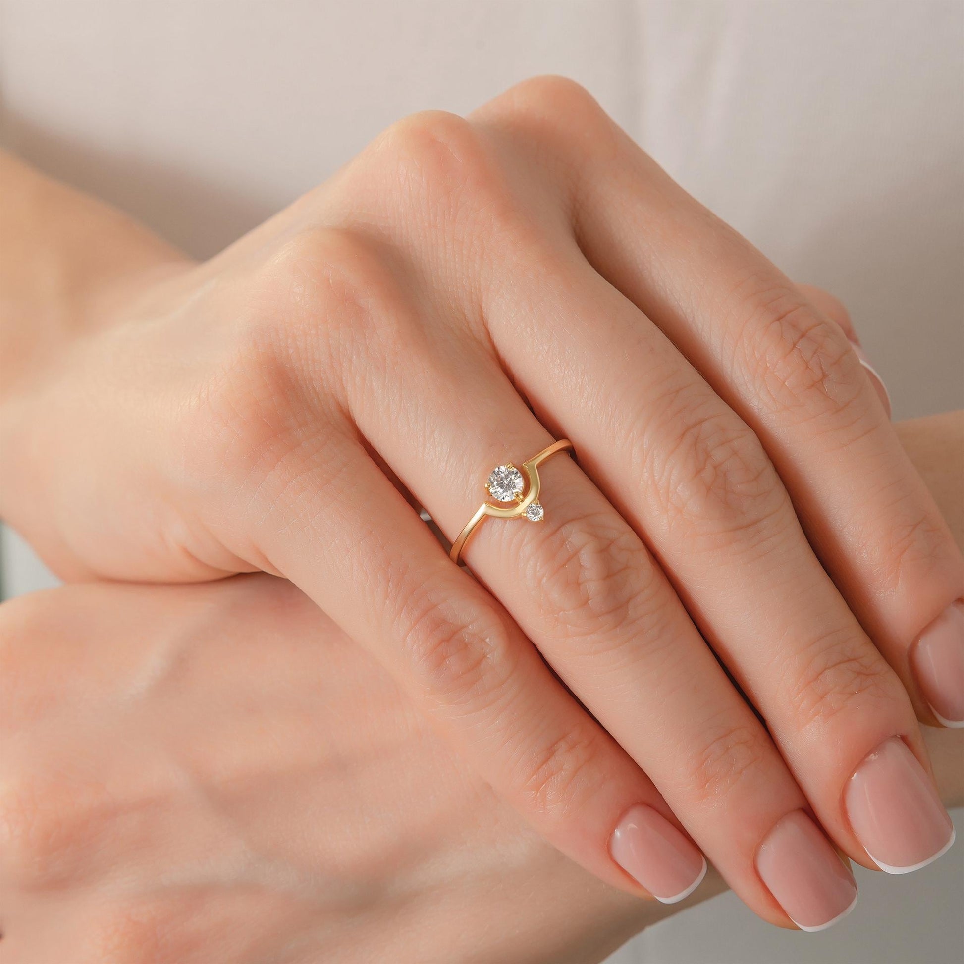 A close-up image of a person's hand wearing a gold ring with a small diamond.