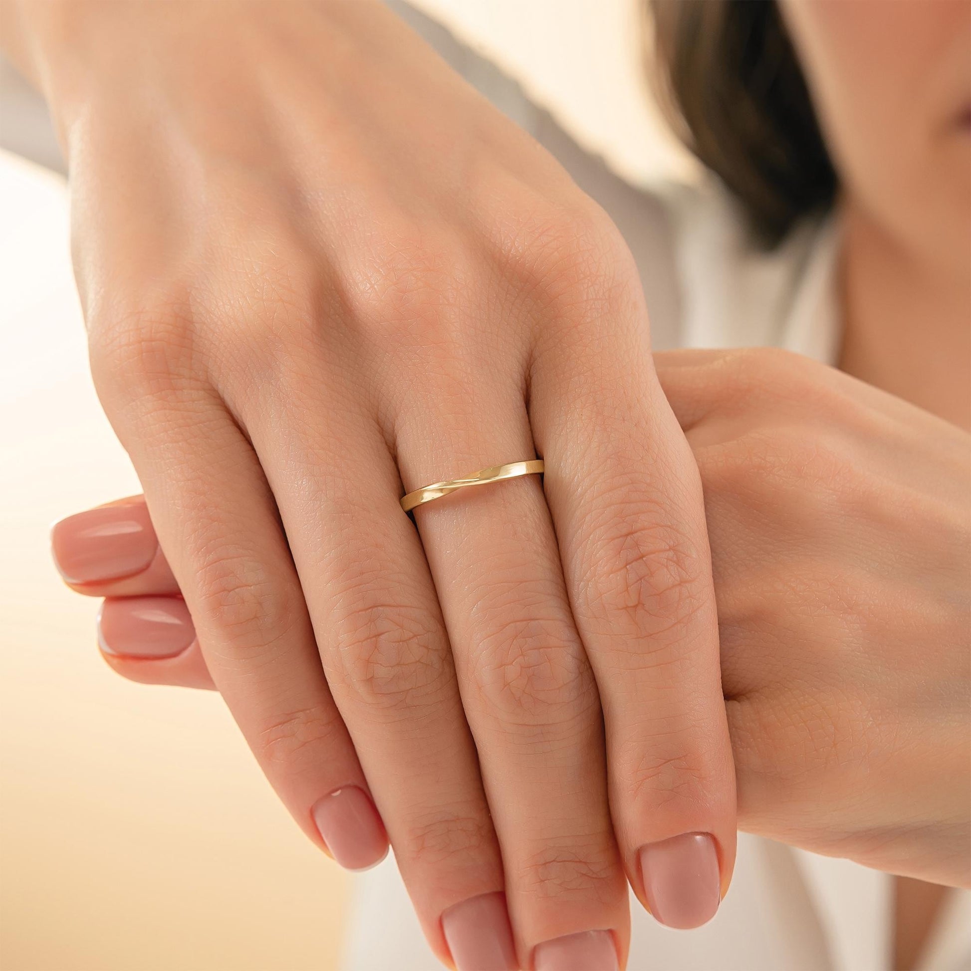 A close-up image of a person's hands wearing a gold ring.