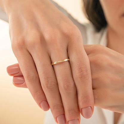 A close-up image of a person's hands wearing a gold ring.