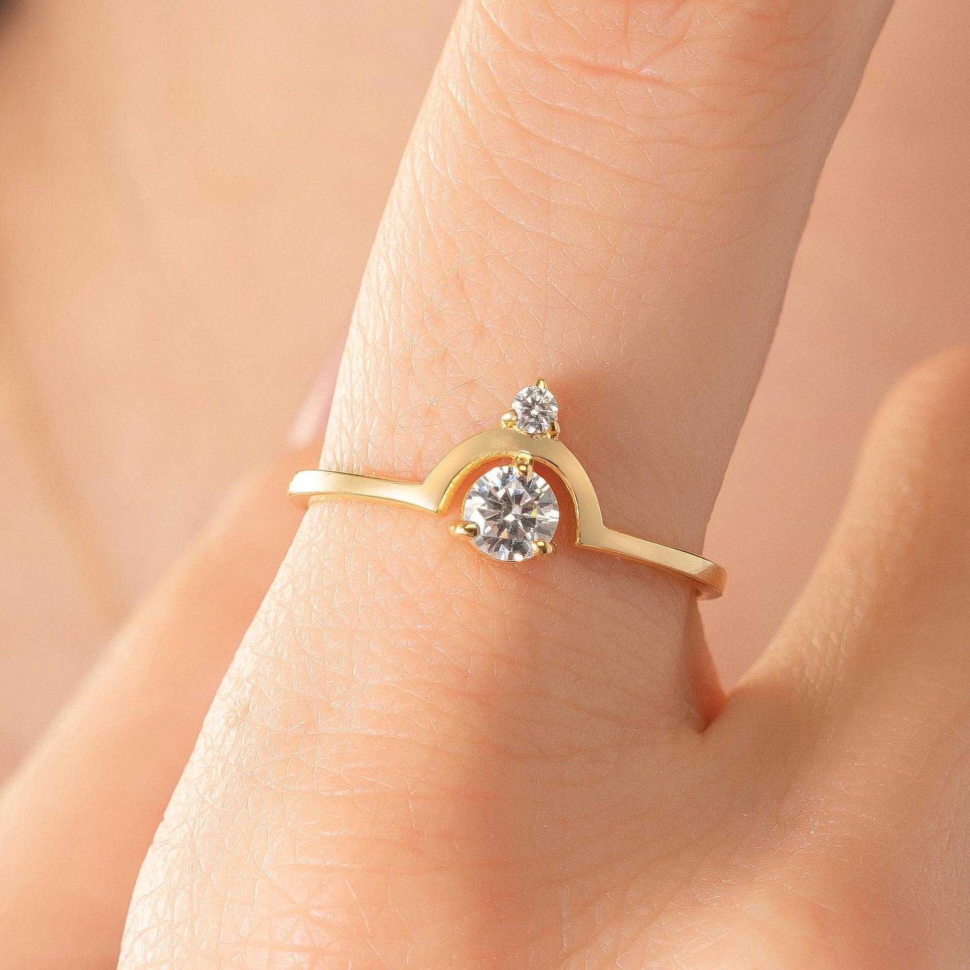 A close-up of a gold ring with a large diamond set in the center, worn on a person's hand.