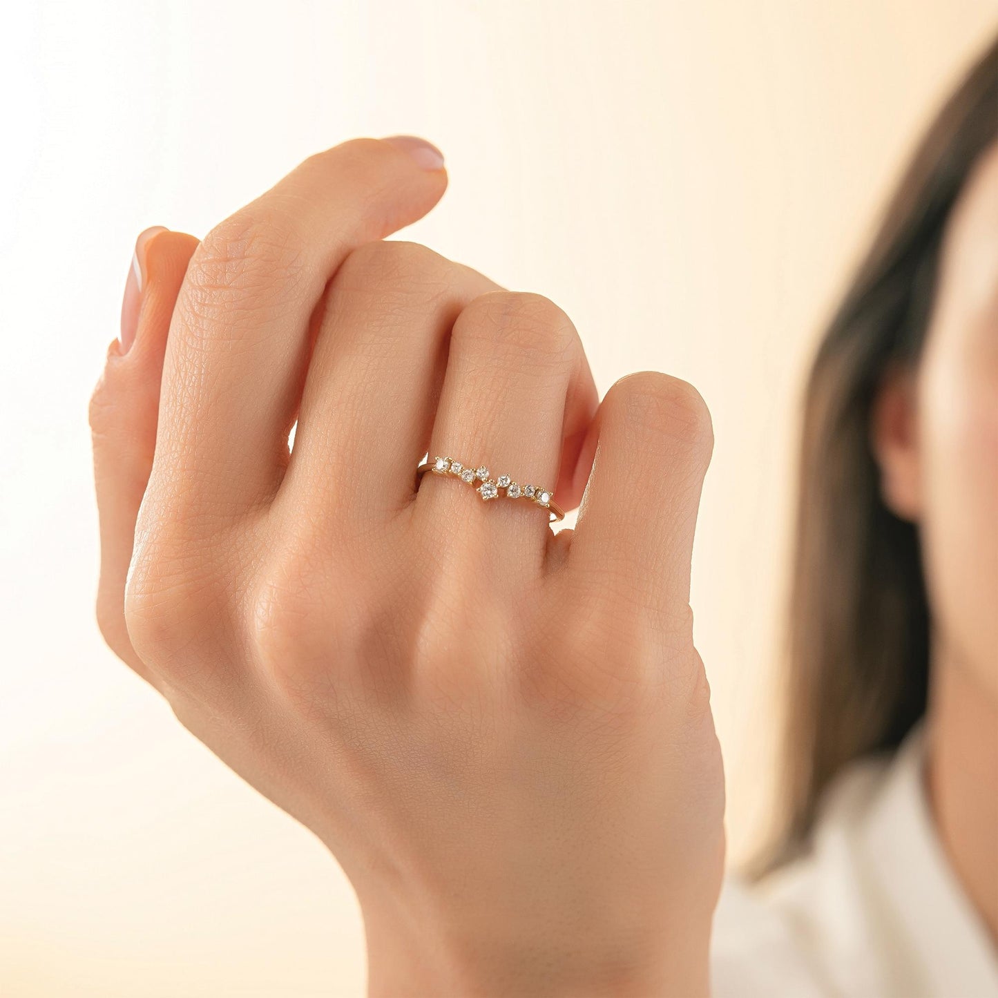 A close-up of a person's hand wearing a ring with a small diamond cluster.