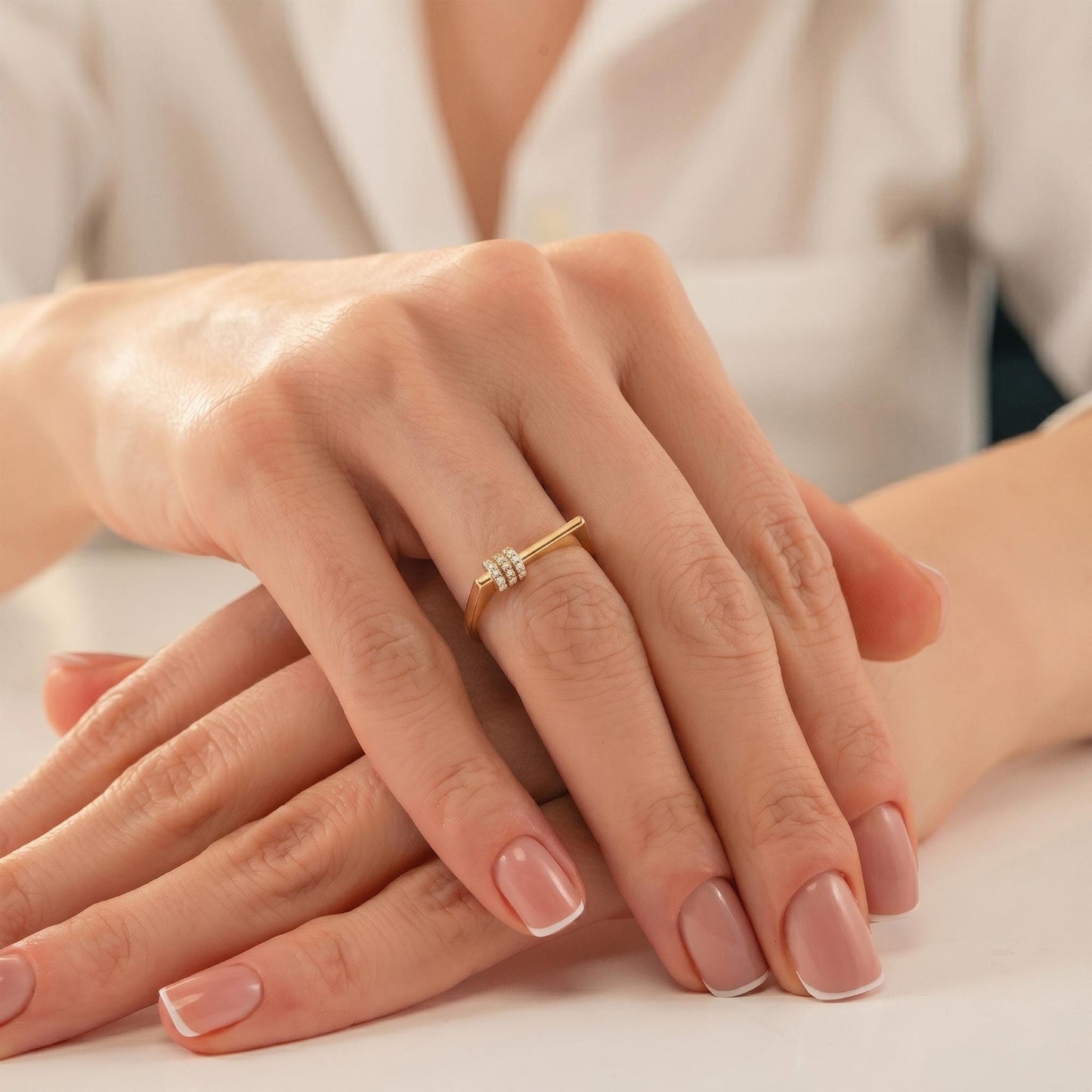 A close-up image of a person's hands resting on a table, with a gold ring visible on one of the fingers.