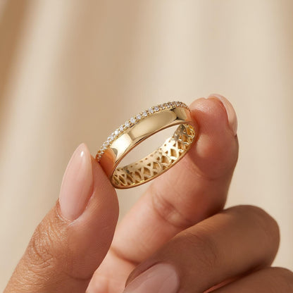 A close-up image of a person's hand holding a gold ring with a diamond accent.