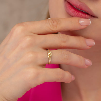 A close-up of a person's hand wearing a gold ring, with their fingers gently curled around it.