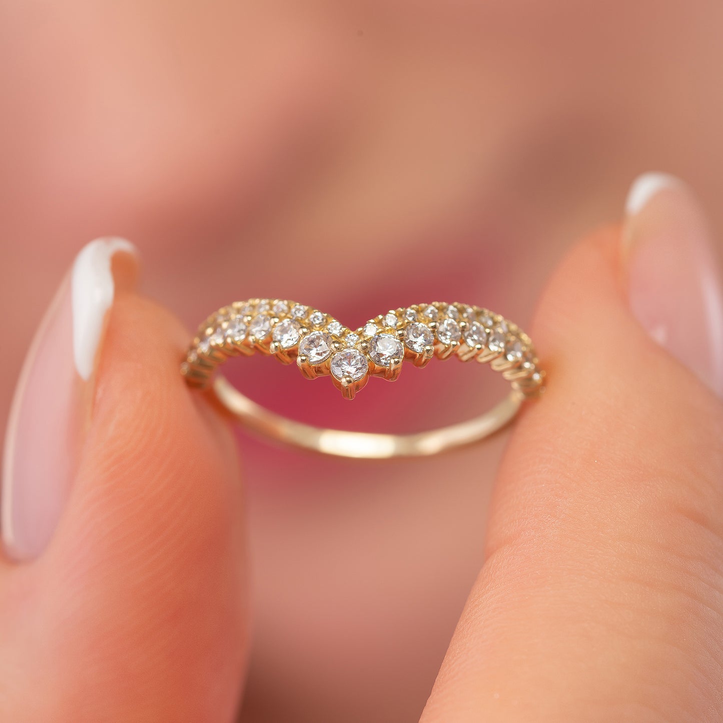 A close-up image of a person's fingers holding a gold ring with a diamond-encrusted band.