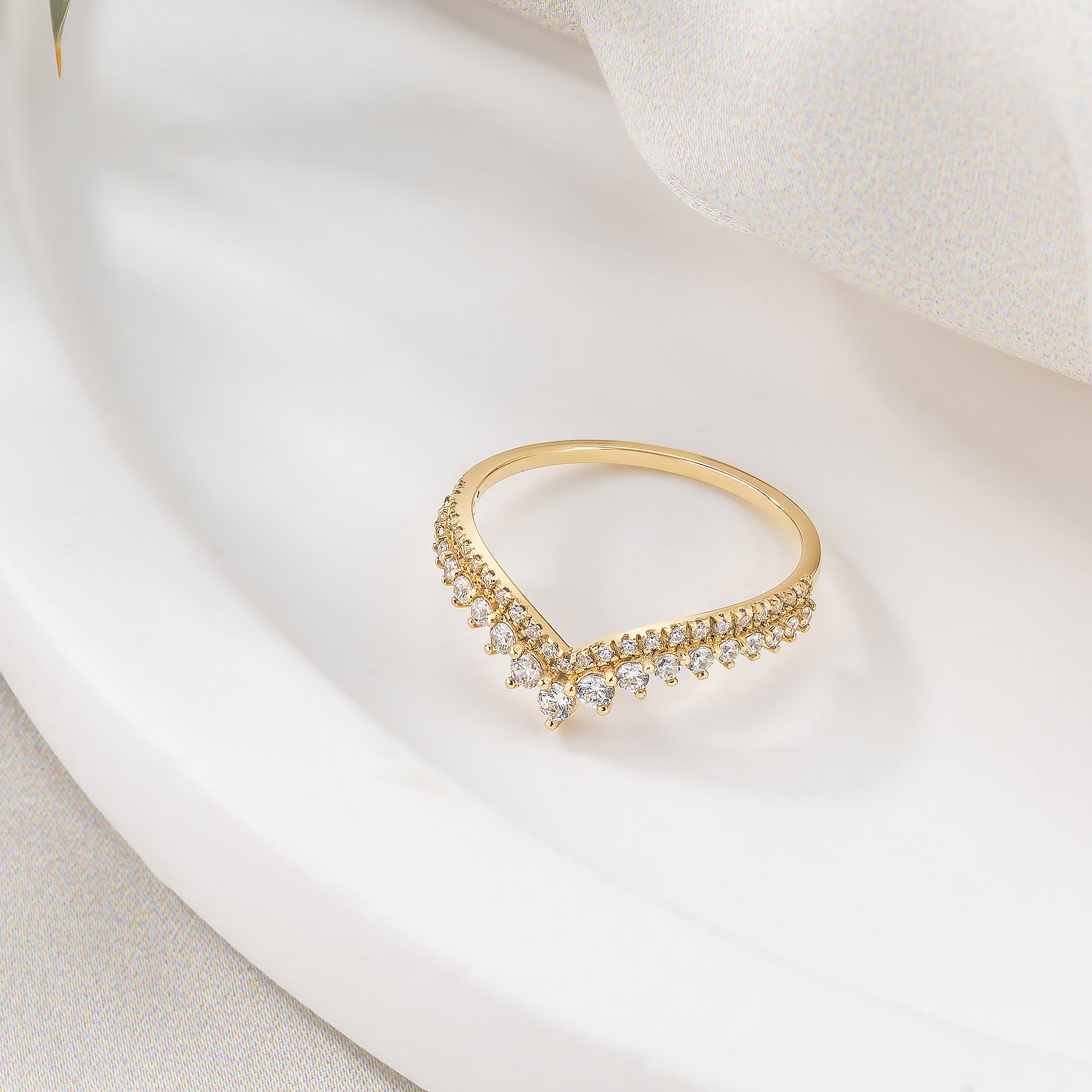 A gold ring with a diamond-encrusted band is displayed on a white surface.