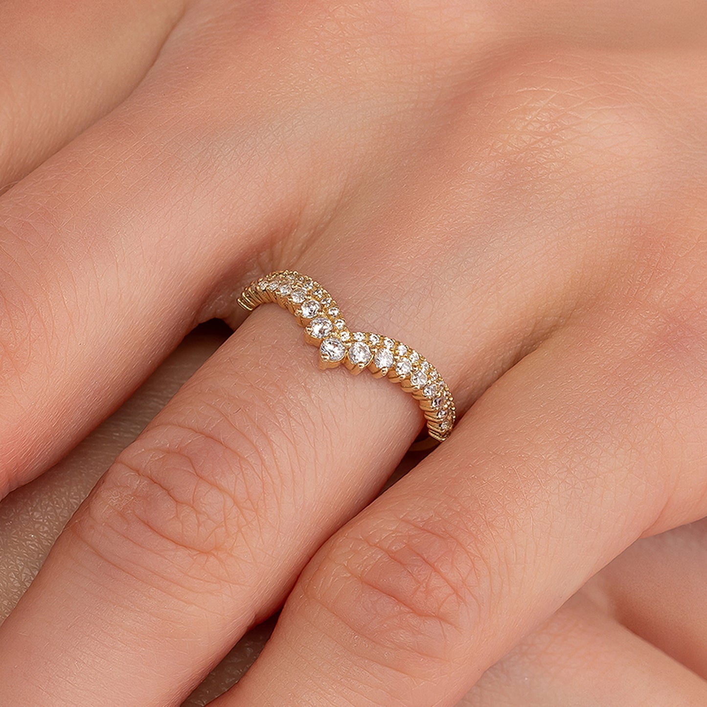 A close-up image of a gold ring with a diamond-encrusted band, resting on a person's hand.