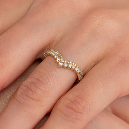 A close-up image of a gold ring with a diamond-encrusted band, resting on a person's hand.
