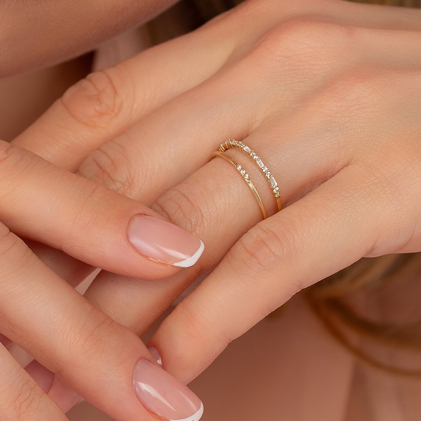 A close-up of a person's hands wearing a gold ring with a diamond accent.